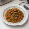 Nouilles sautées au poulet caramélisé sur une assiette garnie.